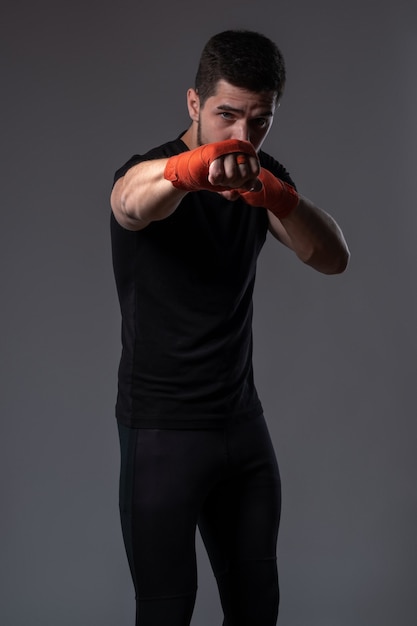 Joven boxeador realizar jab derecho con la mano envuelta en cinta roja