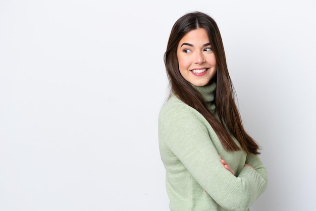 Joven brasileña aislada de fondo blanco mirando hacia un lado y sonriendo