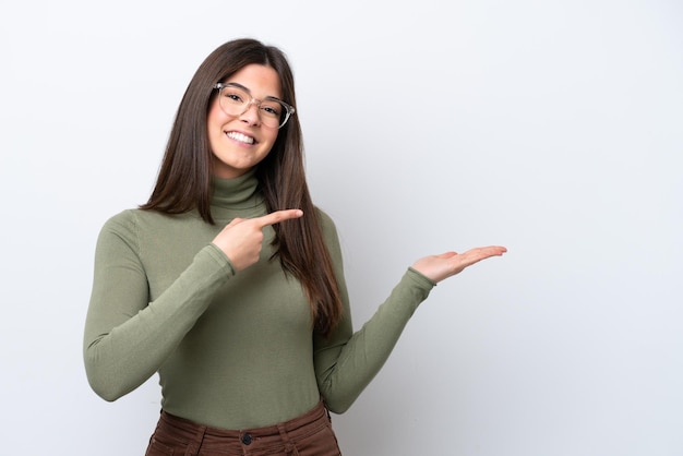 Joven brasileña aislada de fondo blanco sosteniendo un espacio de copia imaginario en la palma de la mano para insertar un anuncio