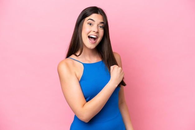 Joven brasileña aislada de fondo rosa celebrando una victoria