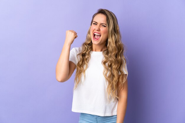 Foto joven brasileña aislada en púrpura celebrando una victoria