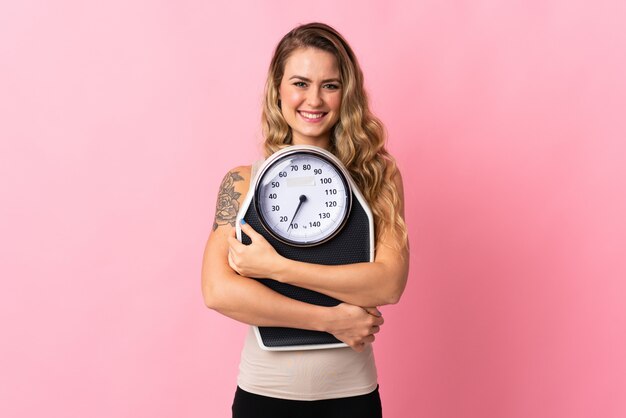 Joven brasileña aislada en rosa con máquina de pesaje