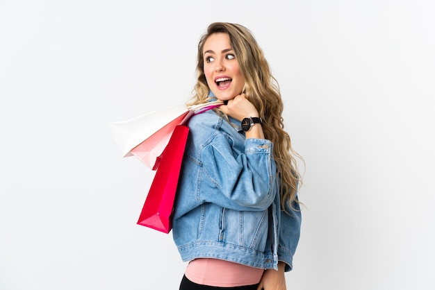 Joven brasileña aislada sobre fondo blanco sosteniendo bolsas de compras y sonriendo