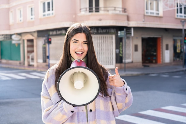 Joven brasileña al aire libre sosteniendo un megáfono con el pulgar hacia arriba