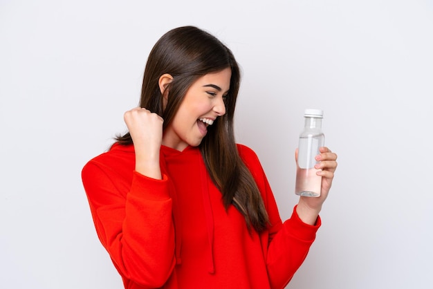 Joven brasileña con una botella de agua aislada de fondo blanco celebrando una victoria