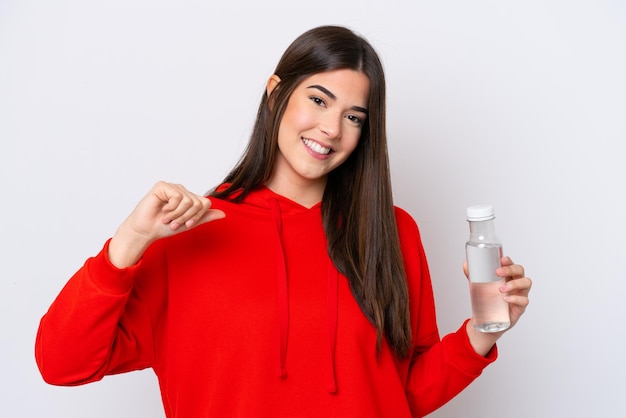 Joven brasileña con una botella de agua aislada de fondo blanco orgullosa y satisfecha