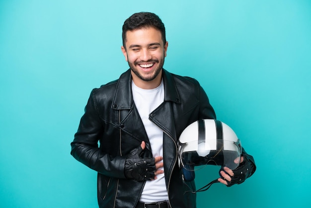 Joven brasileña con un casco de motocicleta aislado de fondo azul sonriendo mucho