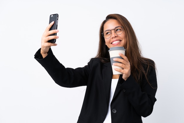 Joven brasileña de negocios con móvil y sosteniendo café para llevar