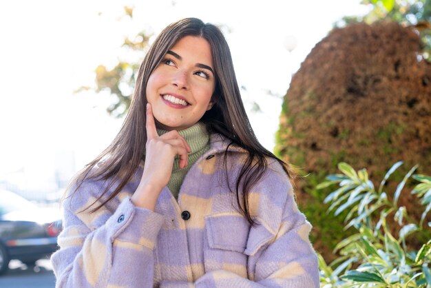 Joven brasileña en un parque pensando en una idea mientras mira hacia arriba