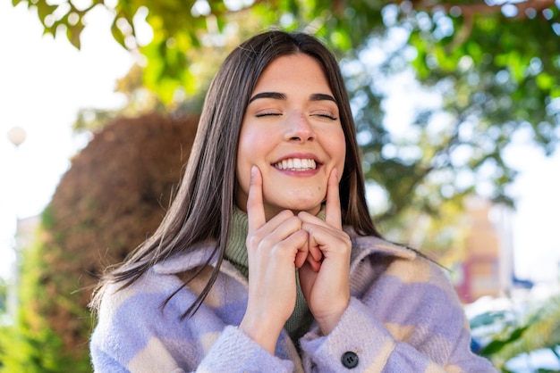 Foto joven brasileña en un parque sonriendo con una expresión feliz y agradable