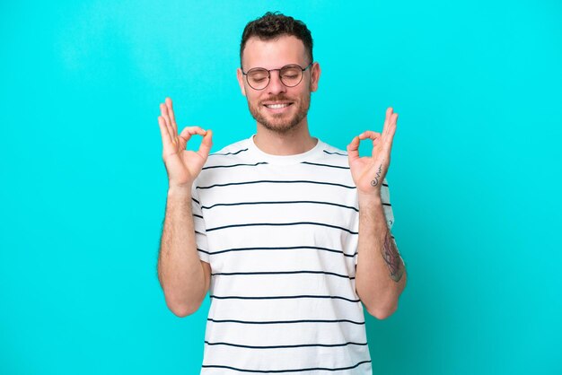 Foto joven brasileño aislado de fondo azul en pose zen