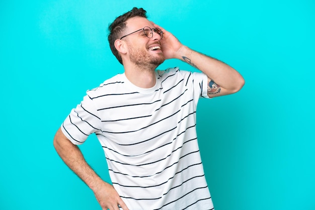 Joven brasileño aislado de fondo azul sonriendo mucho