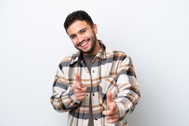 Joven brasileño aislado de fondo blanco apuntando al frente y sonriendo