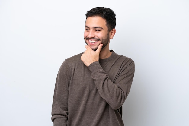 Joven brasileño aislado de fondo blanco mirando hacia un lado y sonriendo