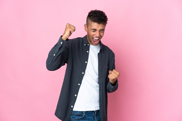 Joven brasileño aislado en rosa celebrando una victoria