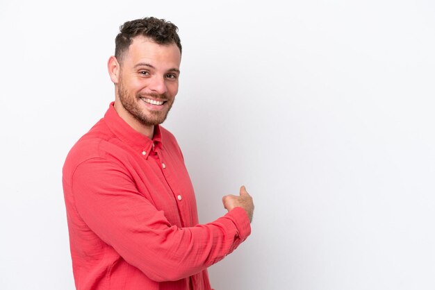 Foto joven brasileño aislado sobre fondo blanco apuntando hacia atrás