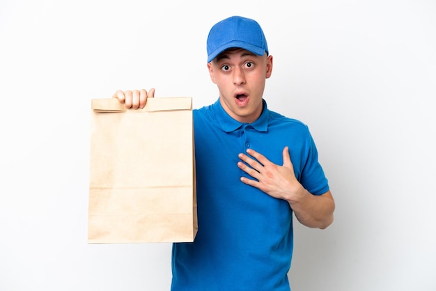 Joven brasileño tomando una bolsa de comida para llevar aislado de fondo blanco sorprendido y conmocionado mientras miraba a la derecha