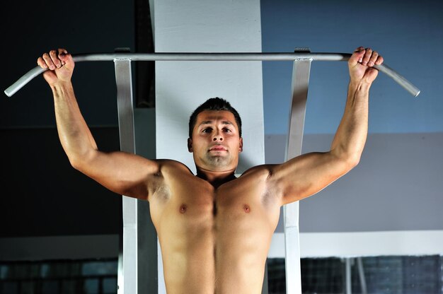 joven con brazos fuertes haciendo ejercicio en el gimnasio y representando su fuerza y vitalidad