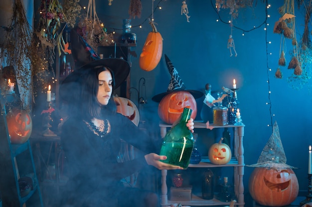 Joven bruja conjura durante Halloween en casa