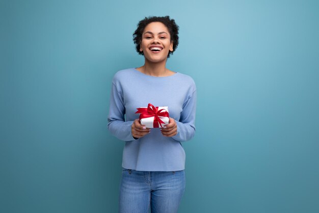 Foto una joven bruneta latina con una caja de regalos con un lazo.