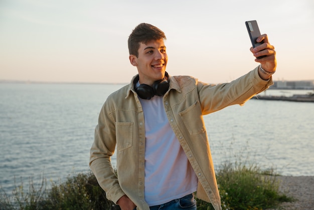 Joven busca música con su teléfono móvil y escucha con auriculares al aire libre