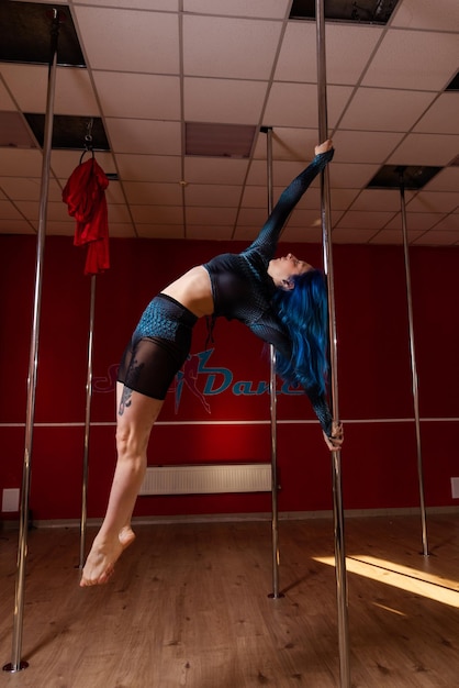 Foto una joven de cabello azul trabajando en un estudio de pole dance