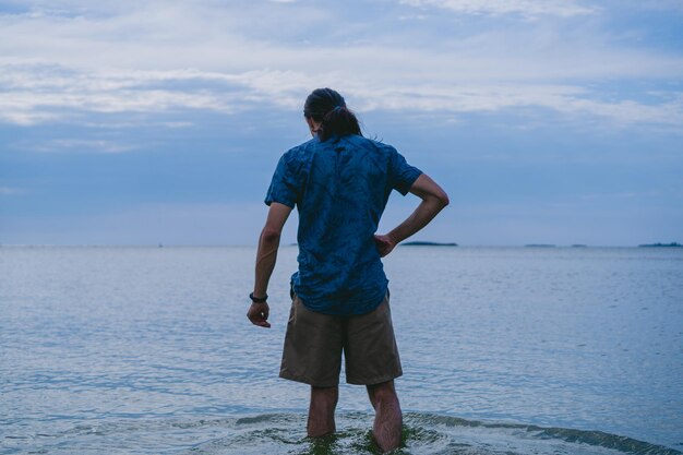 Joven con cabello largo en el Río de la Plata en Colonia del Sacramento Uruguay con agua hasta las rodillas