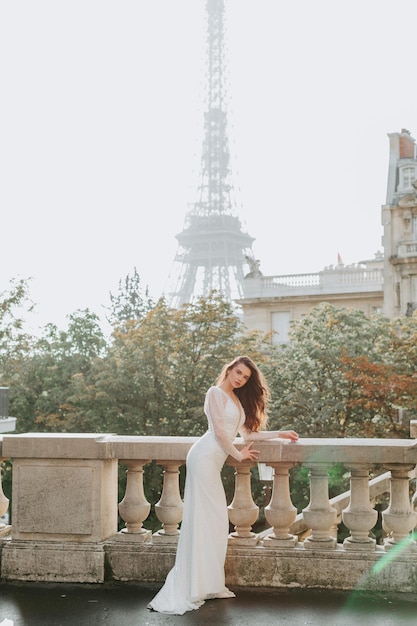 La joven de cabello oscuro está parada frente a la Torre Eiffel