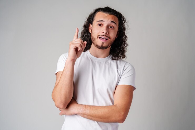 Foto un joven de cabello rizado hace gestos hacia arriba mientras expresa una idea reflexiva