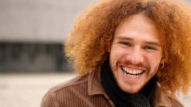 Un joven con el cabello rizado sonriendo a la cámara