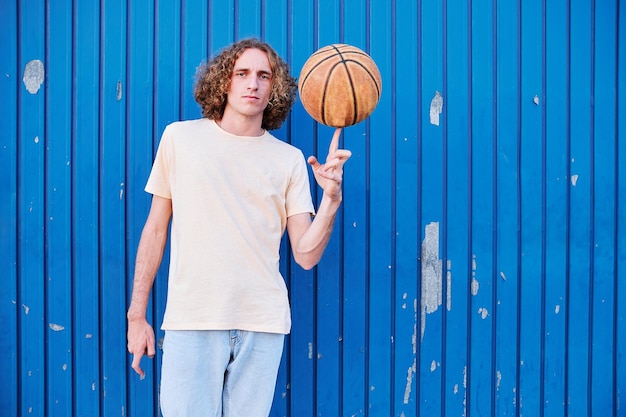 Joven con cabello rizado con su pelota de baloncesto en la mano