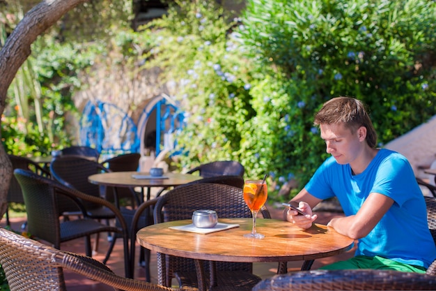 Joven en café al aire libre hablando por teléfono