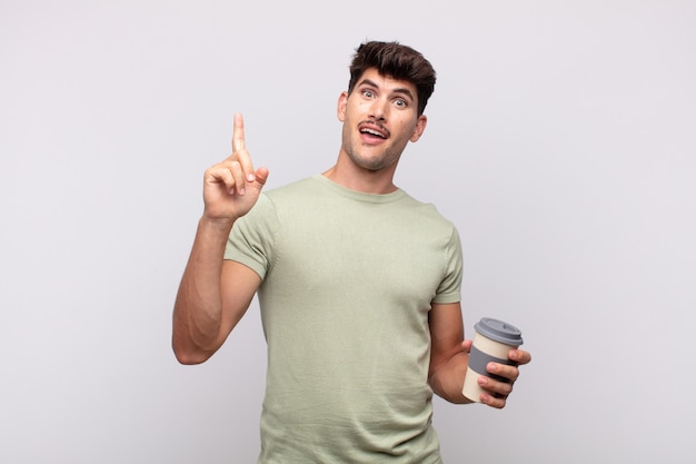 Joven con un café sintiéndose como un genio feliz y emocionado después de darse cuenta de una idea, levantando alegremente el dedo, ¡eureka!