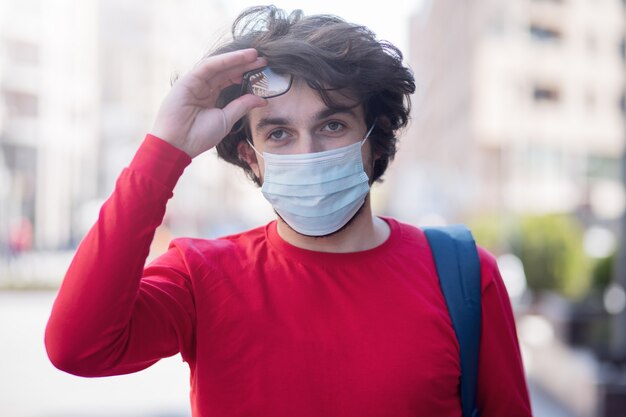 Un joven en la calle se encuentra en una máscara y gafas.