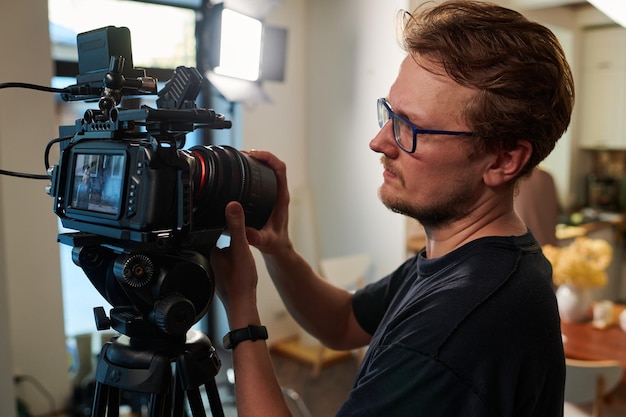 Joven camarógrafo o camarógrafo ajustando el enfoque de su cámara de video