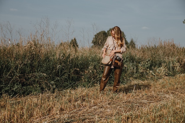 Una joven camina con una cámara retro y toma fotografías de la naturaleza.