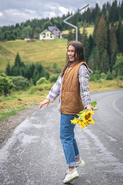 Una joven camina por las montañas con un ramo de girasoles.