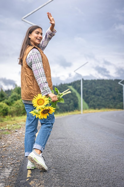 Una joven camina por las montañas con un ramo de girasoles.