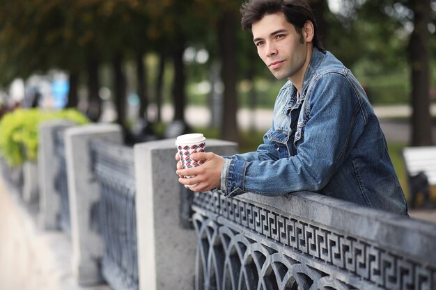 Un joven camina por el parque a la hora del almuerzo. Un hombre está paseando por la ciudad. Un estudiante en el parque.