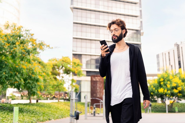 Joven caminando por la ciudad usando un teléfono móvil