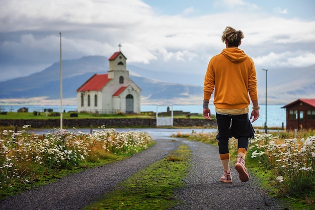 Joven caminando hacia una iglesia y un cementerio en islandia