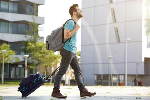 Joven caminando con maleta y bolso