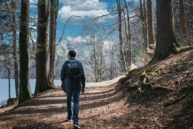 Foto el joven está caminando en medio del bosque en otoño con el cielo nublado en el fondo