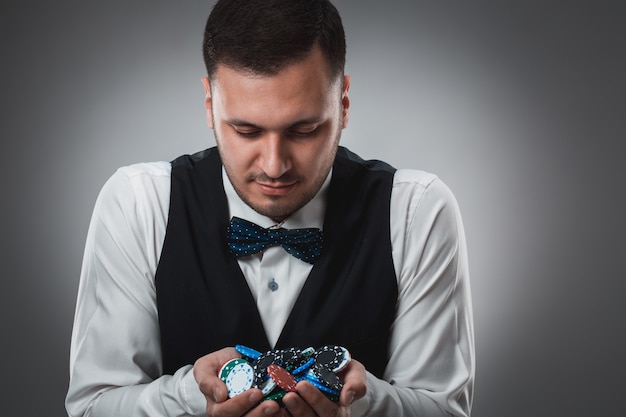 Joven en camisa y chaleco muestra sus fichas de póquer, Foto de estudio