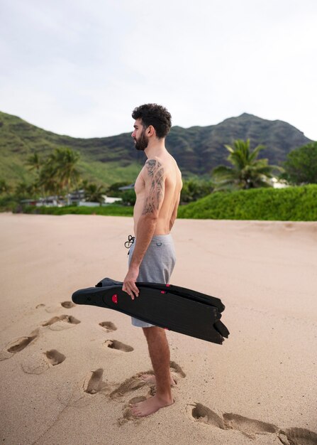 Foto joven sin camisa en la playa con equipo de buceo