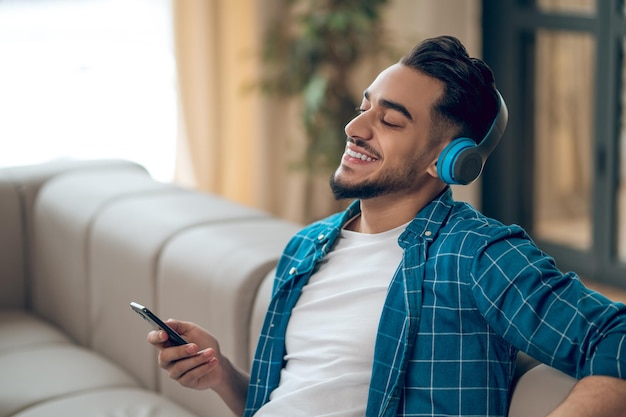 Foto joven con una camiseta azul escuchando música y sintiéndose bien