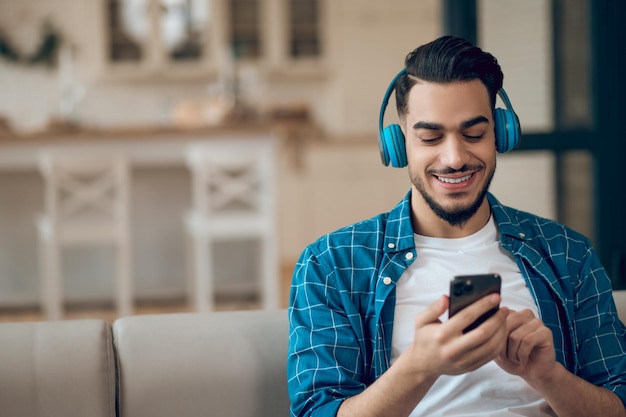 Joven con una camiseta azul escuchando música y sintiéndose bien