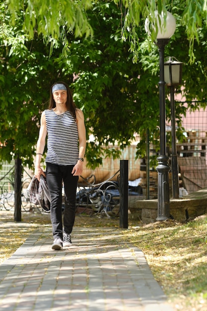 Joven en camiseta sin mangas y jeans camina por la acera