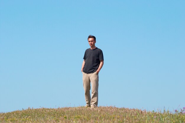 Joven en el campo de hierba con cielo azul