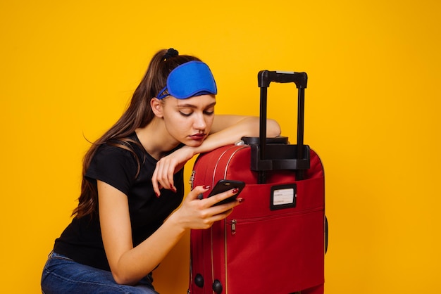 Una joven cansada espera mucho su avión con una maleta, quiere unas vacaciones en el mar